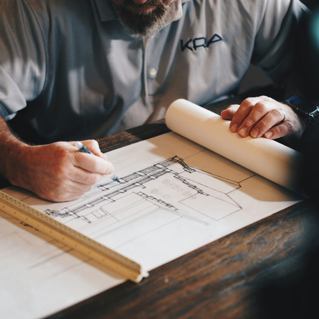 Man Sketching Blueprint photo by Daniel Mccullough